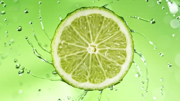 Slice Lime Water Splashes Green Background Isolated Studio Shot Fresh — Stock fotografie