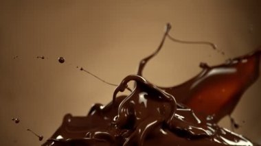 Super Slow Motion of Melted Chocolate Splashing in Waves shapes. Isolated on Brown Background. Filmed on High Speed Cinema Camera in 4k, 1000fps.