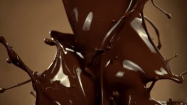 Super Slow Motion of Melted Chocolate Splashing in Waves shapes. Isolated on Brown Background. Filmed on High Speed Cinema Camera in 4k, 1000fps.