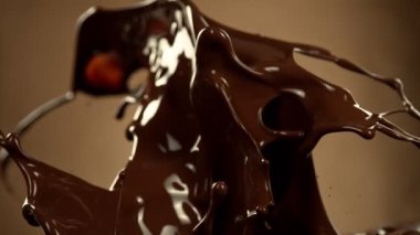 Super Slow Motion of Melted Chocolate Splashing in Waves shapes. Isolated on Brown Background. Filmed on High Speed Cinema Camera in 4k, 1000fps.