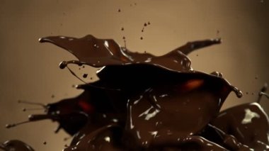 Super Slow Motion of Melted Chocolate Splashing in Waves shapes. Isolated on Brown Background. Filmed on High Speed Cinema Camera in 4k, 1000fps.