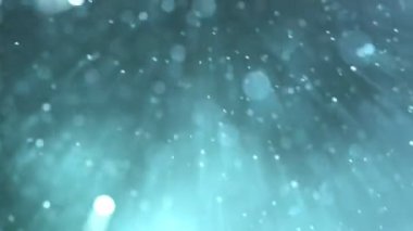 Super slow motion of glittering blue particles on black background. Shallow depth of focus. Abstract shimmering background with glows.