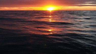 Beautiful ocean waves with sunset horizon. Silhouette of cruiser on background.
