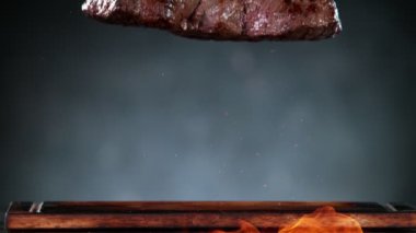 Flying pieces of grilled beef steak with fire falling on table. Filmed on high speed cinema camera, 1000 fps.