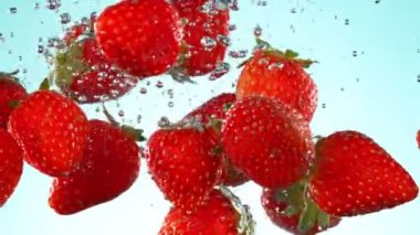 Super slow motion of falling strawberries into water on blue background. Filmed on high speed cinema camera, 1000 fps. Speed ramp effect.