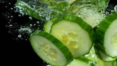 Düşen salatalıkların suya düşmesi çok yavaş bir hareket. Siyah arka planda izole edilmiş. Yüksek hızlı sinema kamerasıyla çekildi, 1000fps. Hız rampası etkisi.