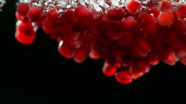 Nar parçalarının suya düşmesi çok yavaş bir hareket. Siyah arka planda izole edilmiş. Yüksek hızlı sinema kamerası, 1000fps