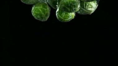 Lahana parçalarının suya düşmesi çok yavaş bir hareket. Siyah arka planda izole edilmiş. Yüksek hızlı sinema kamerası, 1000fps