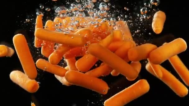 Супер Медленное Движение Падающей Детской Морковки Воду Изолированный Черном Фоне — стоковое видео