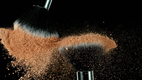 Brown makeup powder on brushes. Isolated on black background.