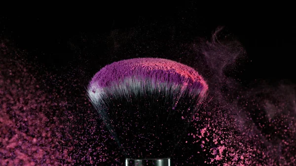 Pink makeup powder on brush. Isolated on black background.