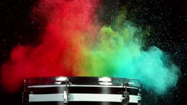Bateristin renkli barut patlamasıyla davullara vuruşunun süper yavaş çekimi. Yüksek hızlı sinema kamerası, 1000 fps..