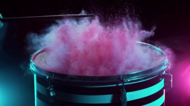 Bateristin renkli barut patlamasıyla davullara vuruşunun süper yavaş çekimi. Yüksek hızlı sinema kamerası, 1000 fps..