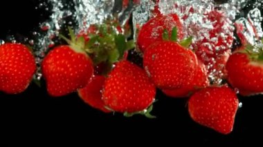 Siyah arka plan üzerinde suya düşen çilek Süper yavaş hareket. Yüksek hızlı sinema kamera, 1000 fps filme.