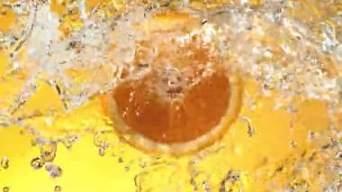 Su Sıçratan Portakal Diliminin Süper Yavaş Hareketi. Dönen Portakal Dilimi ve Sulama Suyu. Renkli Arka plan 'da izole edilmiş. Yüksek Hız Sinema Kamerası, 1000 Fps.