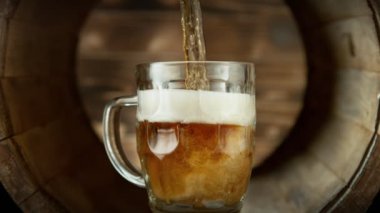 Bardağa bira doldurmanın süper yavaş çekimi. Eski ahşap fıçıya yerleştirilmiş. Yüksek hızlı sinema kamerası, 1000fps.