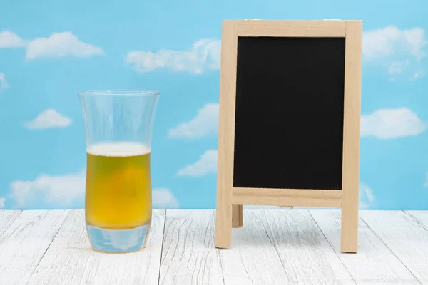 天気の良い日の木製の上に黒板とビールの冷たいガラスは あなたのメッセージのためのコピースペースと空 — ストック写真