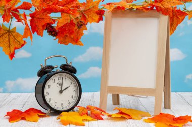 Çalar saat boş beyaz tahta ile yıpranmış ahşap üzerine düşme yaprakları ile mesajınız için kopya alanı ile