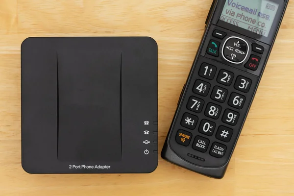Voip 2端口电话适配器和电话放在桌上 供您在家用设备上工作 — 图库照片