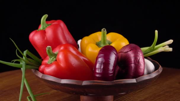 Sweet peppers, red onions, garlic, green onions on a black background — Stock Video