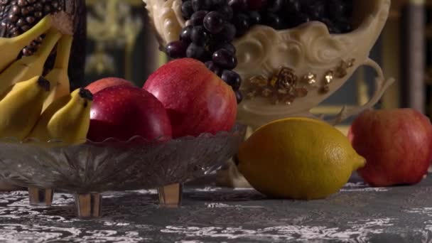 Натюрморт с фруктами. Черный виноград, яблоки, бананы и лимон — стоковое видео