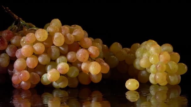 Uvas de color amarillo-rojo con gotas de agua sobre fondo negro — Vídeos de Stock
