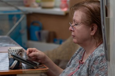 Masada oturan ve akıllı telefona bakan kadın.