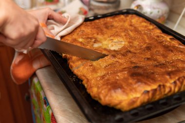 Mutfakta bir kadın pişirdiği turtayı kesiyor.