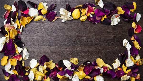 Frame with dry rose petals on wooden background — Stock Photo, Image