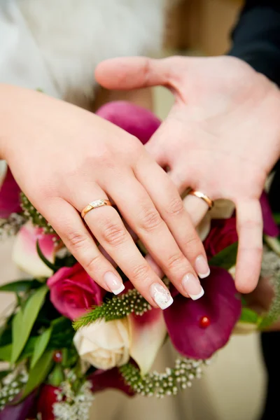 Bouquet and hands with rings — Stock Photo, Image