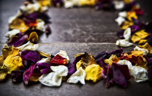 Frame with dry rose petals on wooden background — Stock Photo, Image