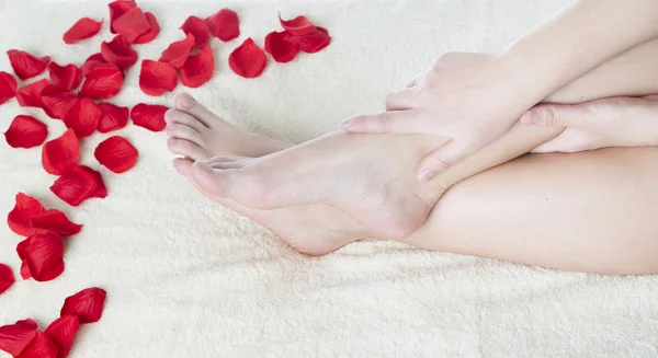 Beautiful female feet and rose petals. — Stock Photo, Image