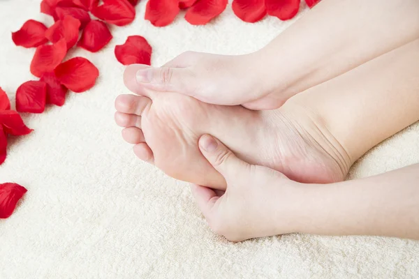 Beautiful female feet and rose petals. — Stock Photo, Image