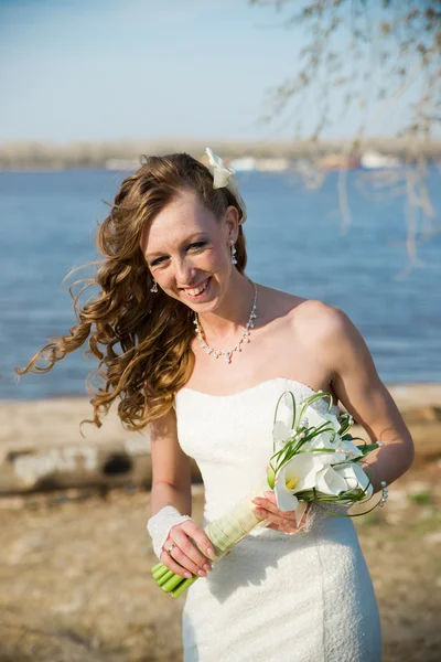 Hermosa novia en un vestido blanco en la costa del río — Foto de Stock