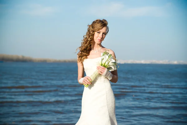 Beautiful bride in a white dress on coast of river — Stock Photo, Image