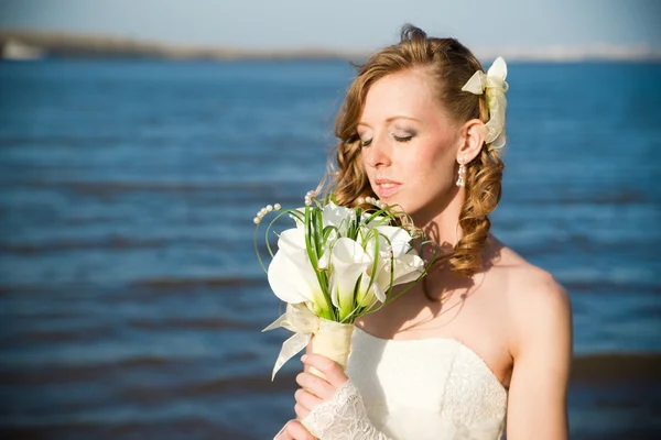 Beautiful bride in a white dress on coast of river — Stock Photo, Image