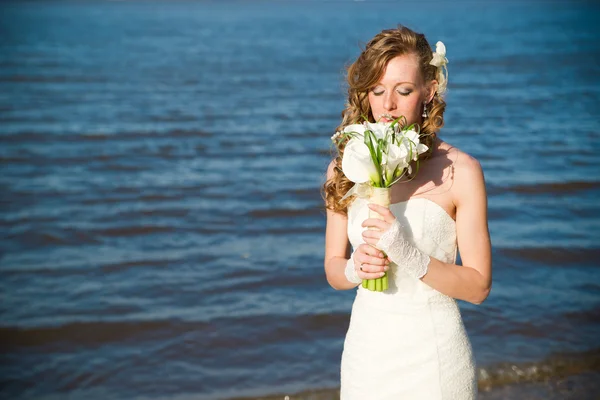 Beautiful bride in a white dress on coast of river — Stock Photo, Image