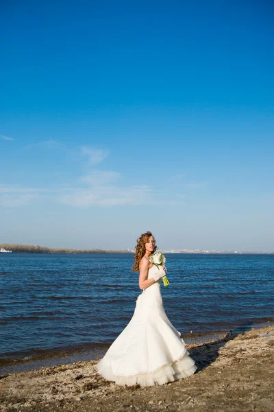 Pięknej narzeczonej w białej sukni na wybrzeżu rzeki — Zdjęcie stockowe