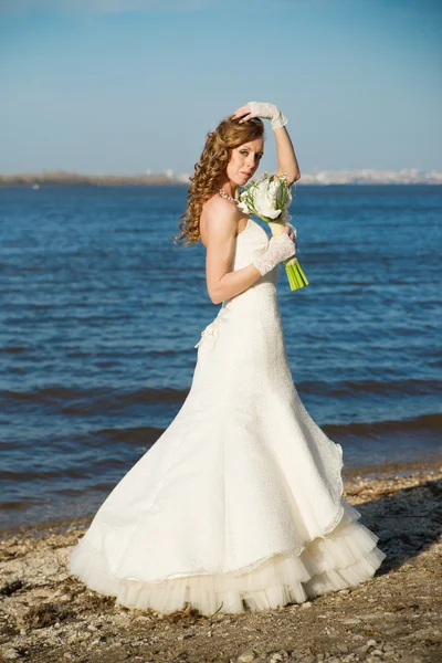 Pięknej narzeczonej w białej sukni na wybrzeżu rzeki — Zdjęcie stockowe