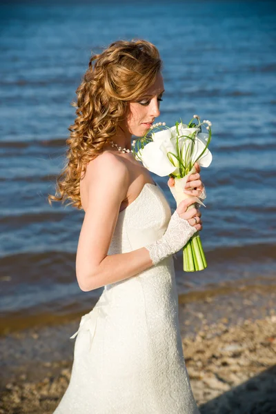 Beautiful bride in a white dress on coast of river — Stock Photo, Image