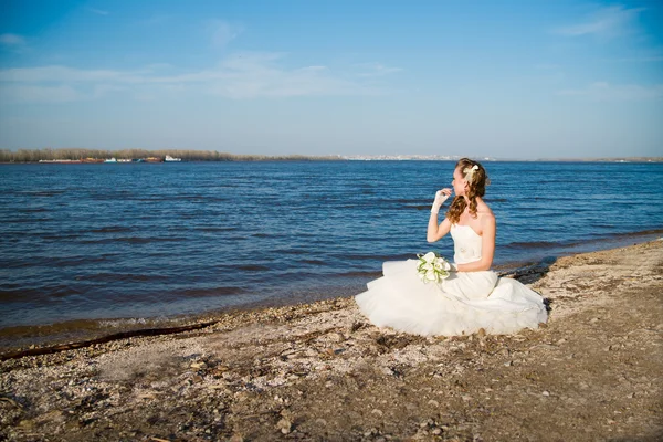 Beautiful bride in a white dress on coast of river — Stock Photo, Image