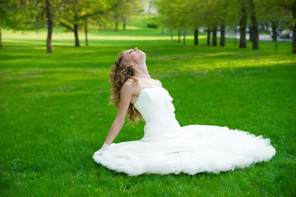 Beautiful bride in a white dress on green grass in summer — Stock Photo, Image