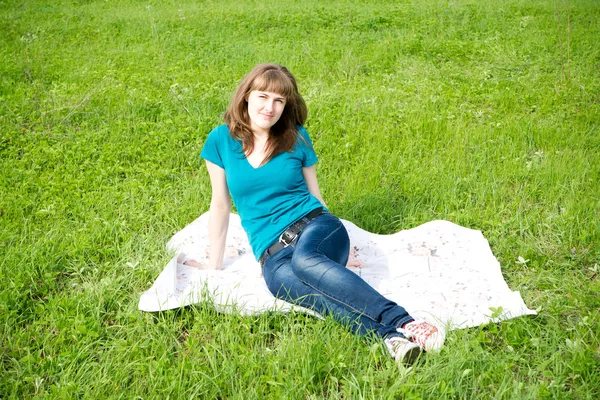 Mooi meisje rusten op het groene gras — Stockfoto