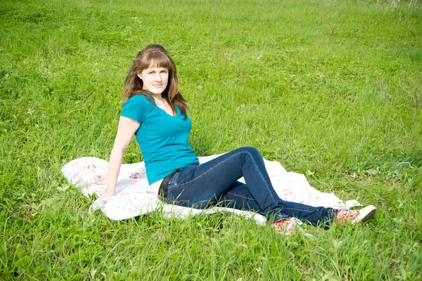 Mooi meisje rusten op het groene gras — Stockfoto