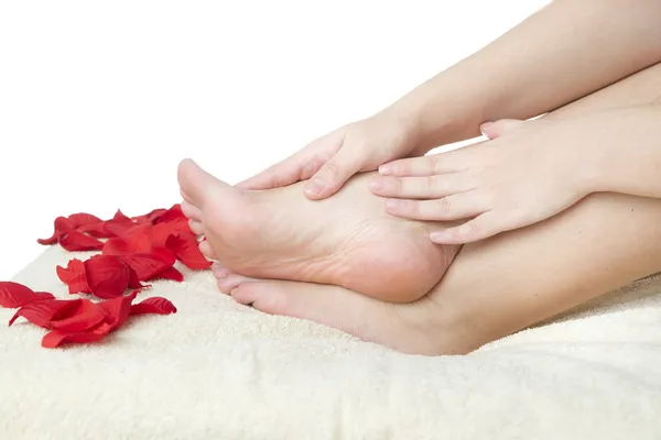 Beautiful female feet and rose petals. — Stock Photo, Image