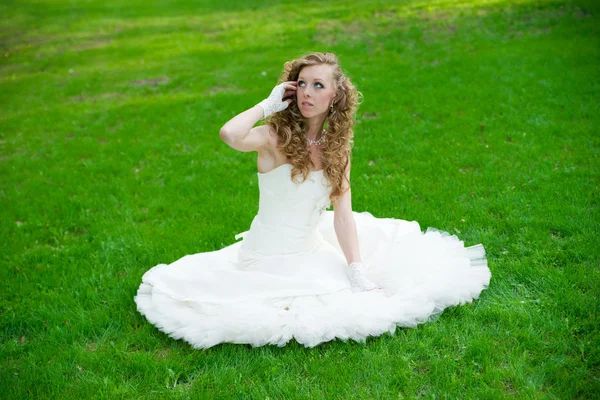 Hermosa novia en un vestido blanco sobre hierba verde en verano — Foto de Stock