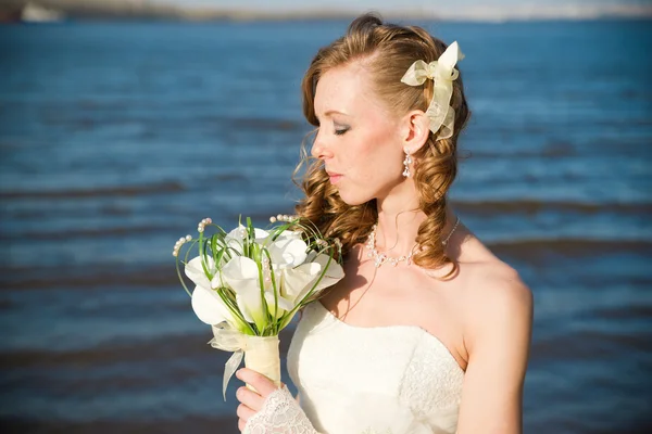 Beautiful bride with a bouquet of calla lilies on coast of river — Stock Photo, Image