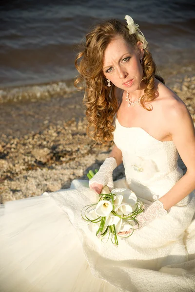 Hermosa novia en un vestido blanco en la costa del río — Foto de Stock