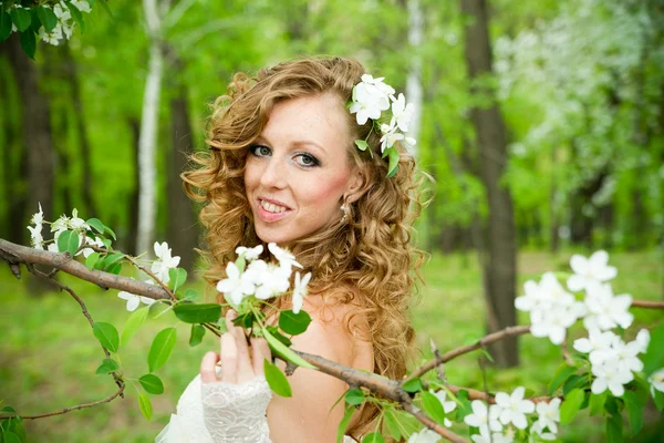 Beautiful bride in a white dress in blooming gardens — Stock Photo, Image