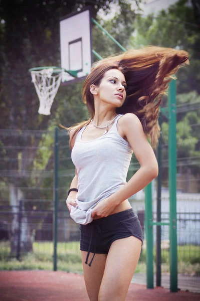 Krásná mladá žena s vlající vlasy hrát basketbal venku — Stock fotografie